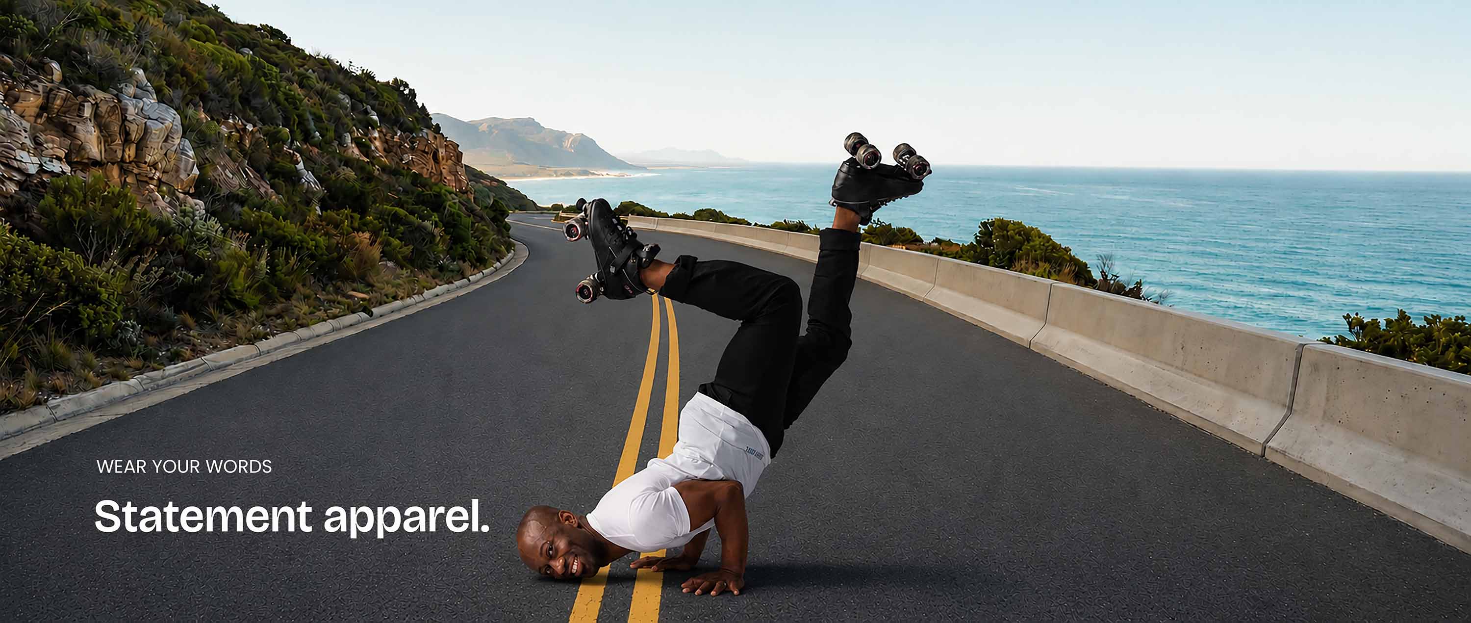 A man is doing a handstand in the middle of a coastal highway on the double yellow lines. He's in roller skates and is wearing a white Bored Rebel t-shirt and black pants rolled up at the ankles. The text overlay reads 'wear your words statement apparel'.