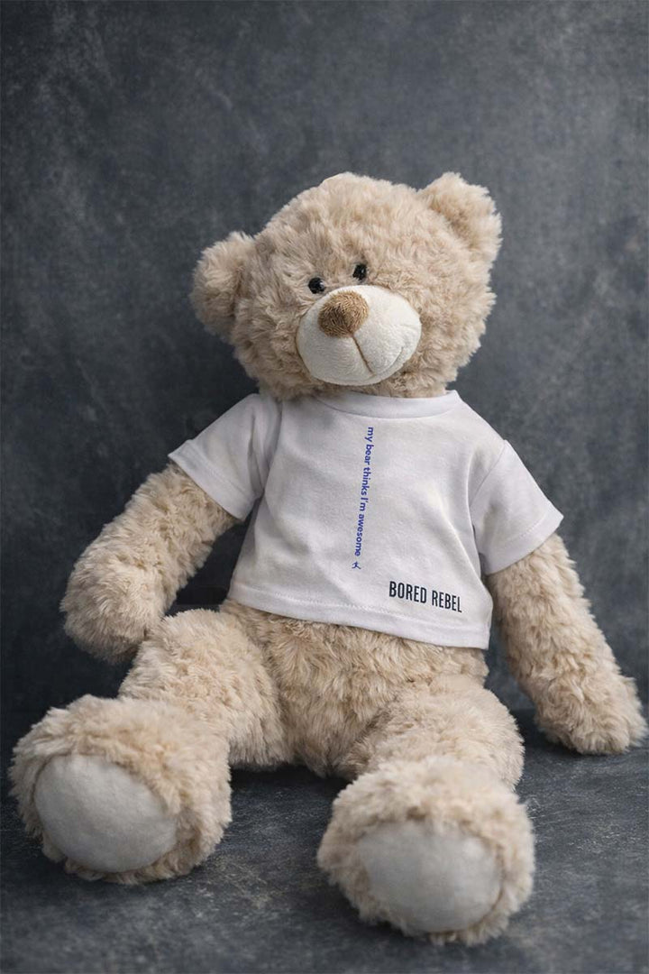 Beige teddy bear wearing a white Bored Rebel t-shirt with text in it that reads &
